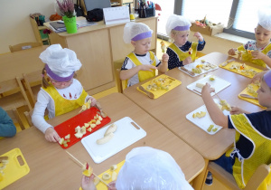 07 Dzieci siedzą przy stoliku i robią szaszłyki z owoców